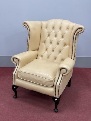 Lot 1536 - Cream Button Back Leather Wing Armchair, with...